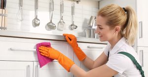 Woman cleaning white cabinets.