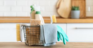 Basket of cleaning supplies on a kitchen counter.