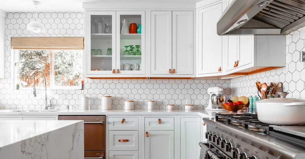 White kitchen with full wall backsplash of hexagon mosaic tiles.