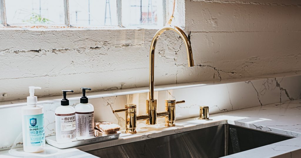 Gold colored kitchen faucet and fixtures in a white retro kitchen.