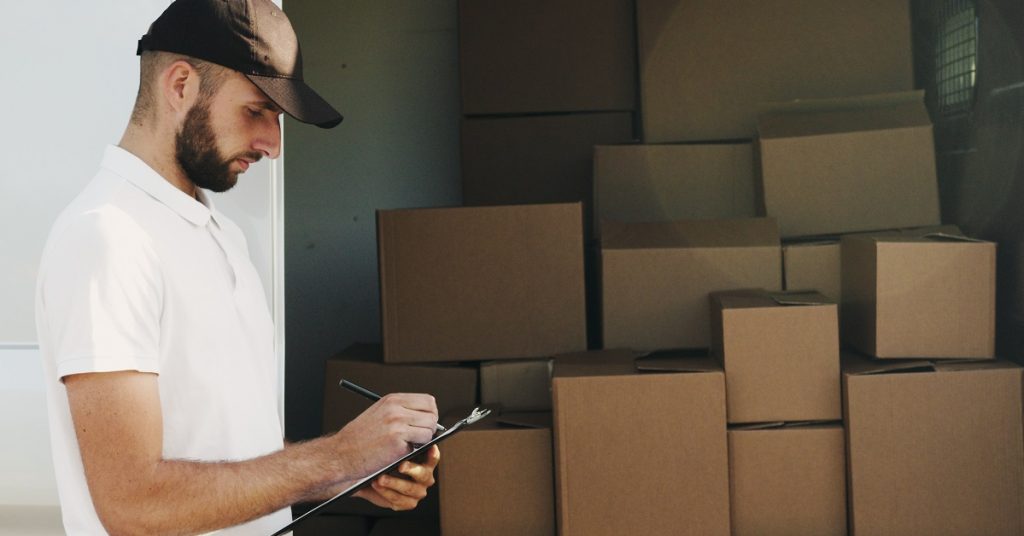 Man checking a shipment and signing paperwork.
