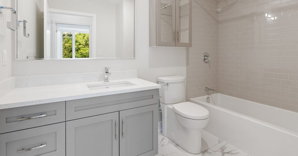 Simple gray shaker cabinet vanity in a white bathroom.