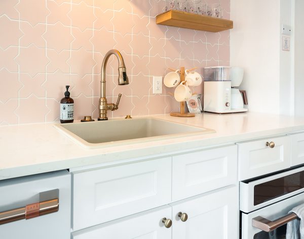 Blush tile backsplash with white shaker cabinets.