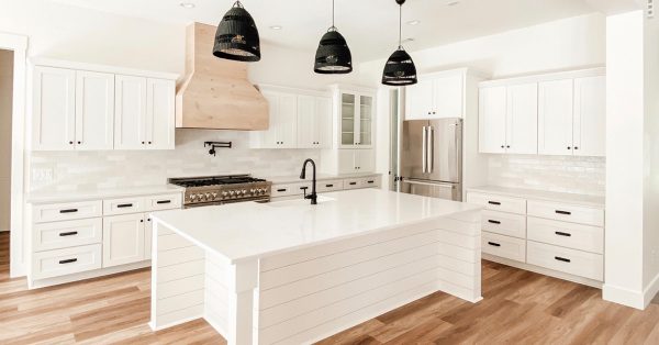 White kitchen with large island and pendant lights.