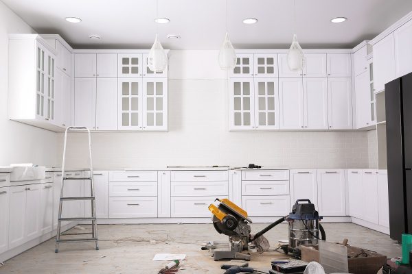 White kitchen undergoing remodeling with new cabinets installed.