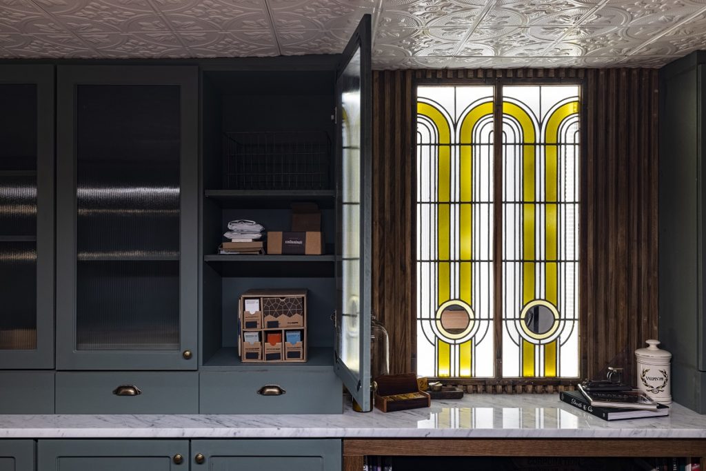 Cabinets that sit on the countertop painted green with marble counters.