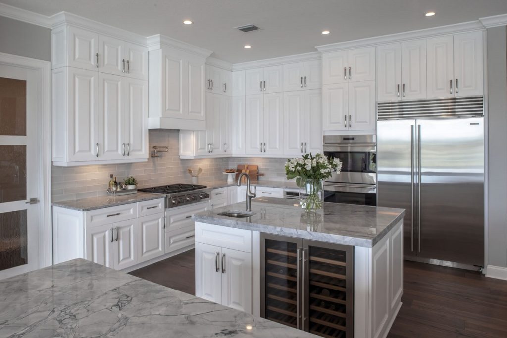 Traditional white cabinets with stainless and marble accents in an open format kitchen.