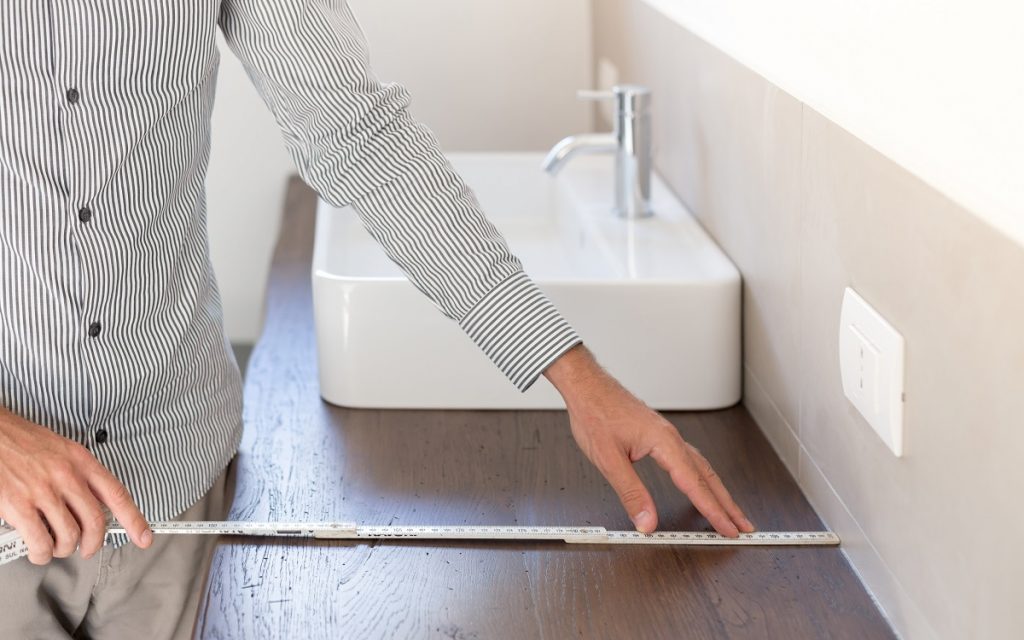 Person measuring the depth of the vanity with a tape measure.