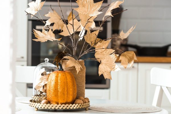 Fall decor like fall leaves and a pumpkin on a kitchen island.