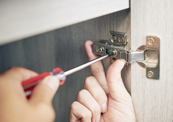 Close up of person installing hinges on a cabinet door.