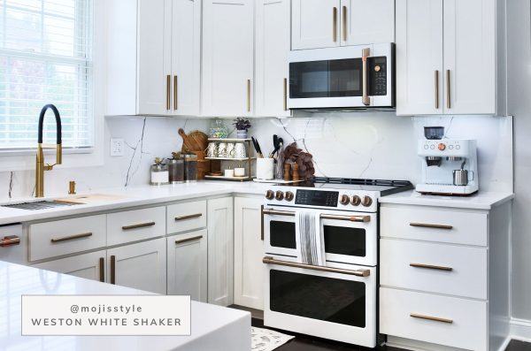White kitchen with white cabinets and long brass handles.