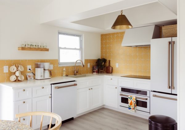 White and yellow kitchen with shaker cabinets and gray wood floor.