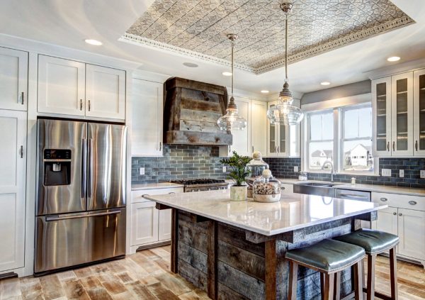 Large kitchen with white cabinets and white countertops with tin tile on the ceiling.
