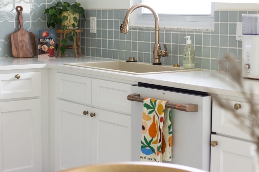 White kitchen with blue backsplash and gold fixtures.