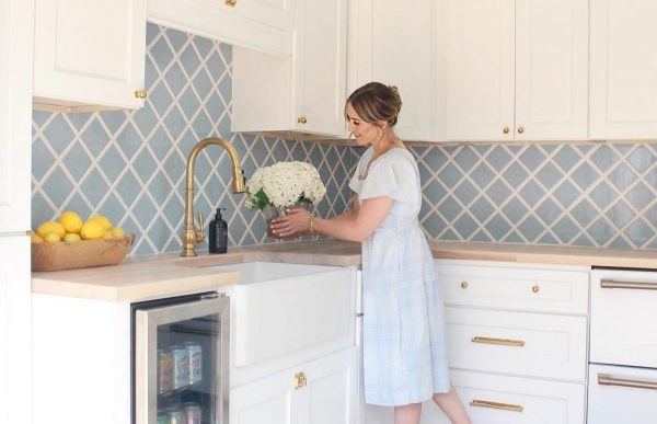 Person arranging flowers in a blue and white kitchen.