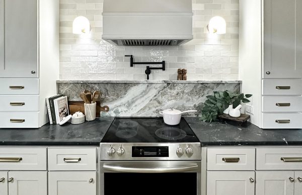 Black and white kitchen with white cabinets and white subway tile on the backsplash.