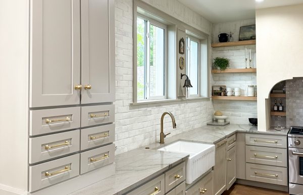 Beige shaker cabinets against a white backsplash with gold hardware and fixtures.