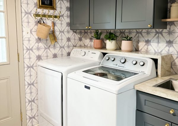 Laundry room with cabinets and geometric wallpaper.
