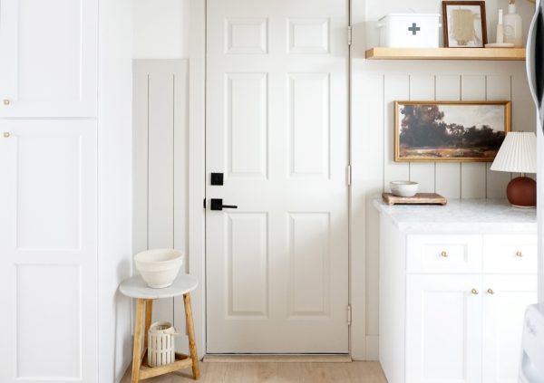 White laundry room with natural wood accents. The room functions as a multi-tasking space with office and mud room as well.