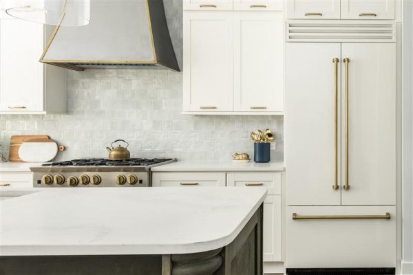 Neutral kitchen with white shaker cabinets and gold hardware.